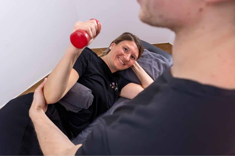 Patientin trainiert mit Hantel während einer physiotherapeutischen Übung unter Anleitung eines Therapeuten beim TVG1893 Essen